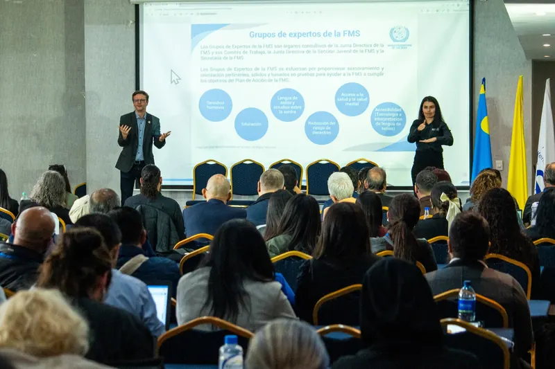 Conferencista e intérprete de lengua de señas ante un auditorio lleno